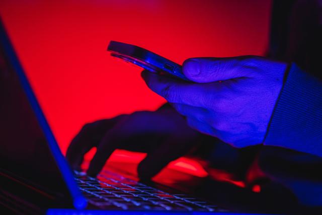 Person am Laptop und Handy in der Nacht
